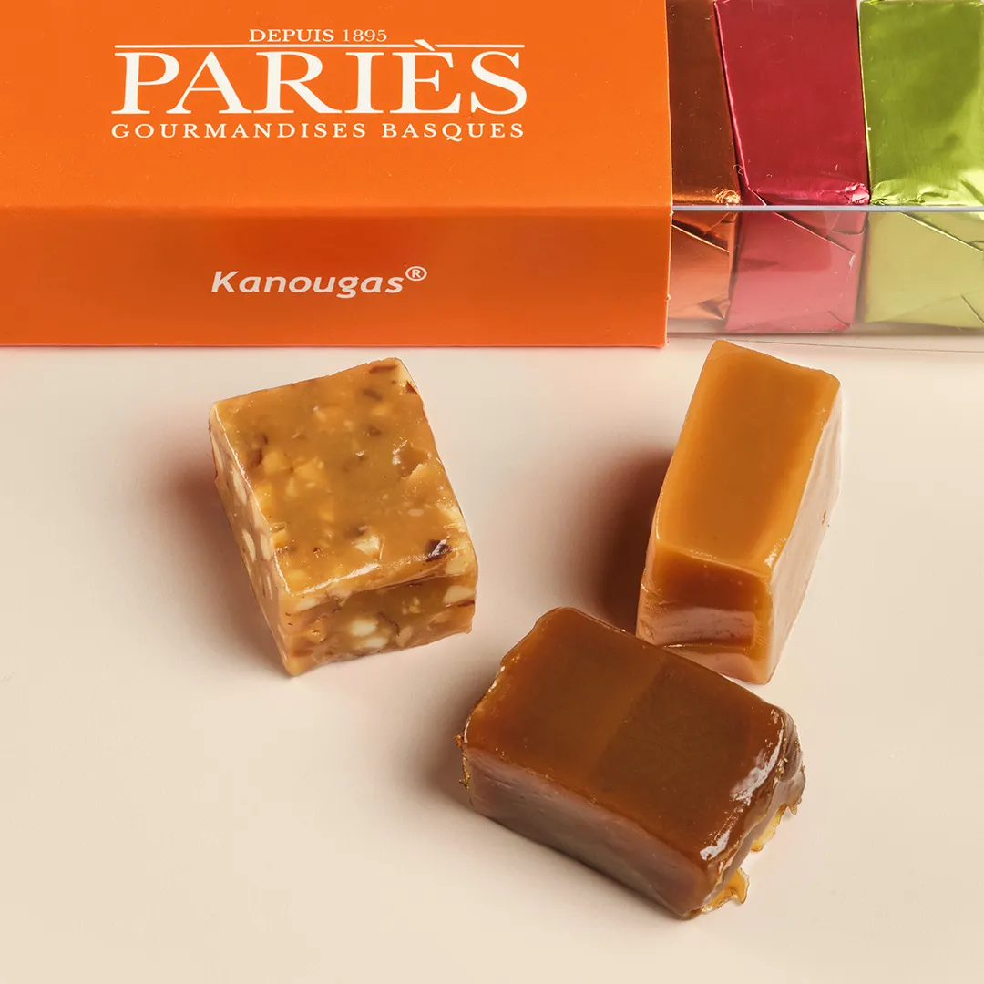Three Kanougas from Pariès house, Basque delicacies from Bordeaux, displayed in front of an orange box with logo since 1895