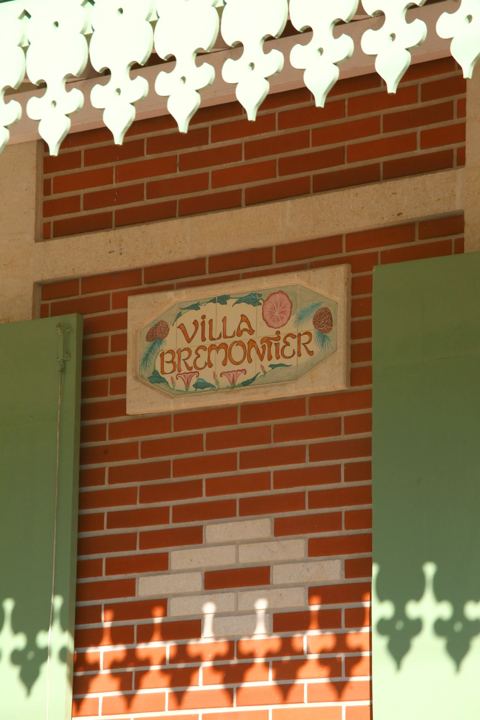 Red brick facade of Villa Bremontier in Bordeaux featuring an ornamental sign and decorative roof crown