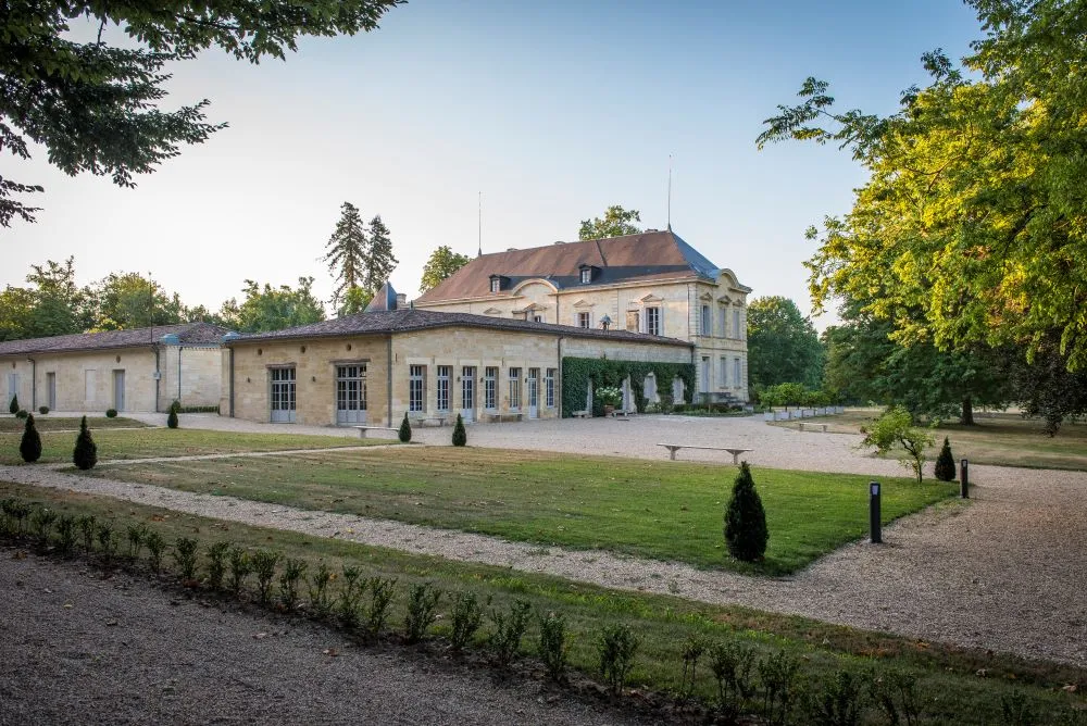 Château Siaurac in Bordeaux featuring classical stone façade, mansard roofs, outbuildings and landscaped grounds with mature trees