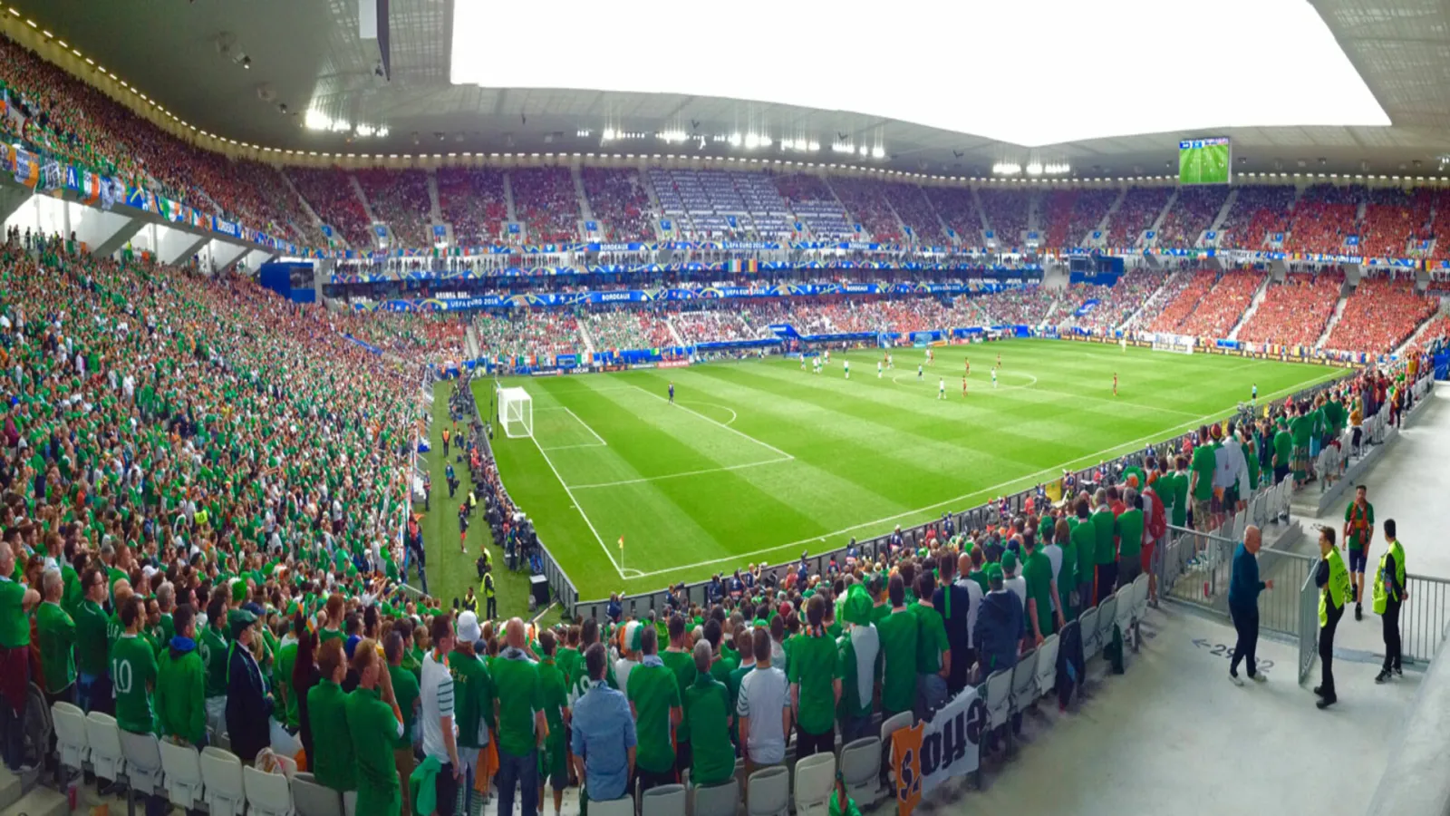 Interior view of Stade Atlantique Bordeaux Métropole filled with supporters wearing green and red jerseys during a football match, with the green pitch and crowded stands.