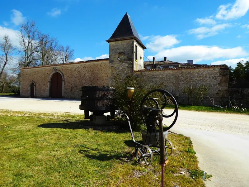 Château de Lisennes near Bordeaux featuring an antique cart in the foreground, stone building with pointed tower under blue sky