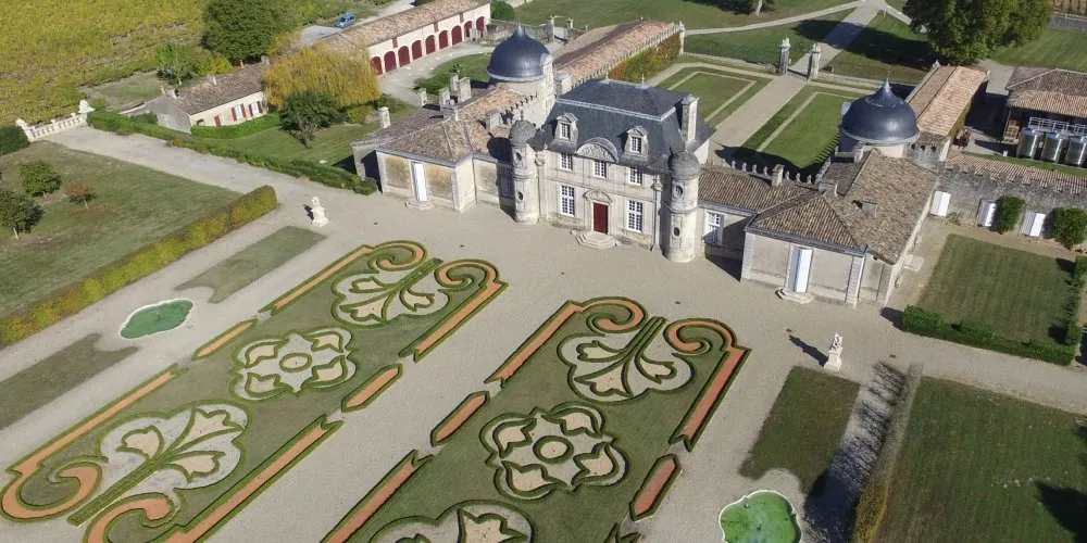 Aerial view of Château de Malle in Bordeaux featuring ornamental parterre gardens with spiral and scroll designs, domed towers, and formal French gardens