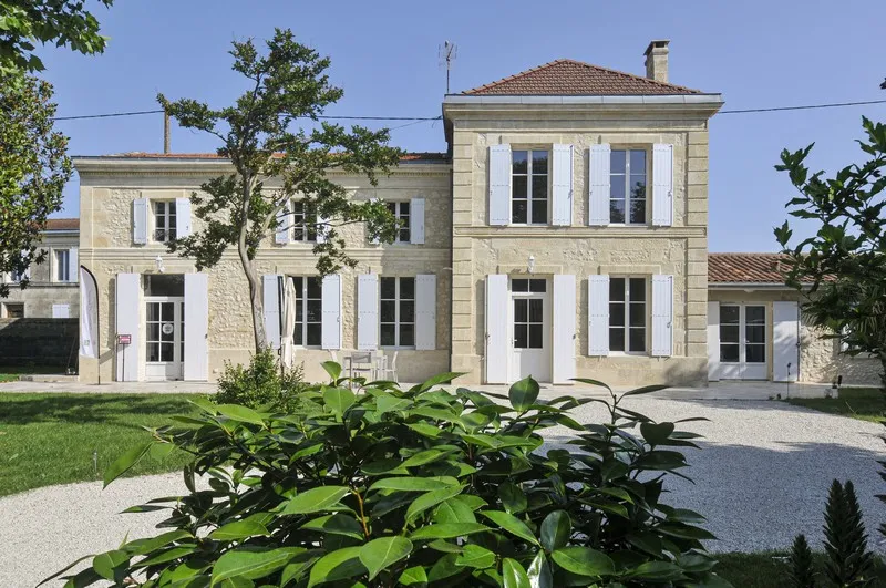 Front facade of Château d'Osmond in Bordeaux, stone building with white shutters, main entrance, and landscaped garden