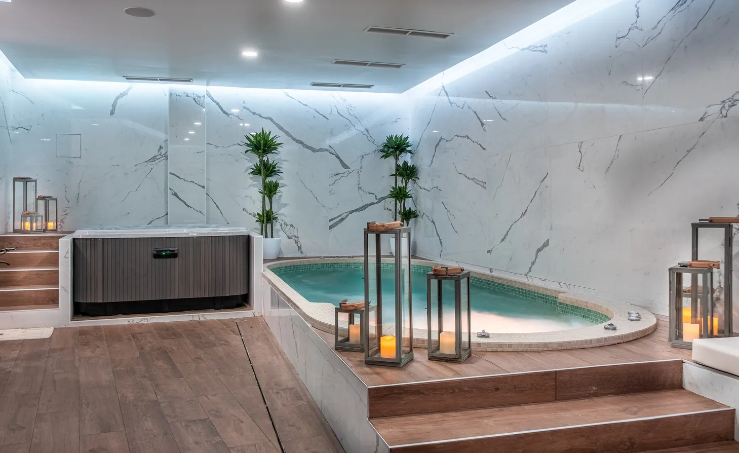 Luxury spa featuring turquoise swimming pool, white veined marble walls, hot tub, green plants, decorative lanterns and modern lighting