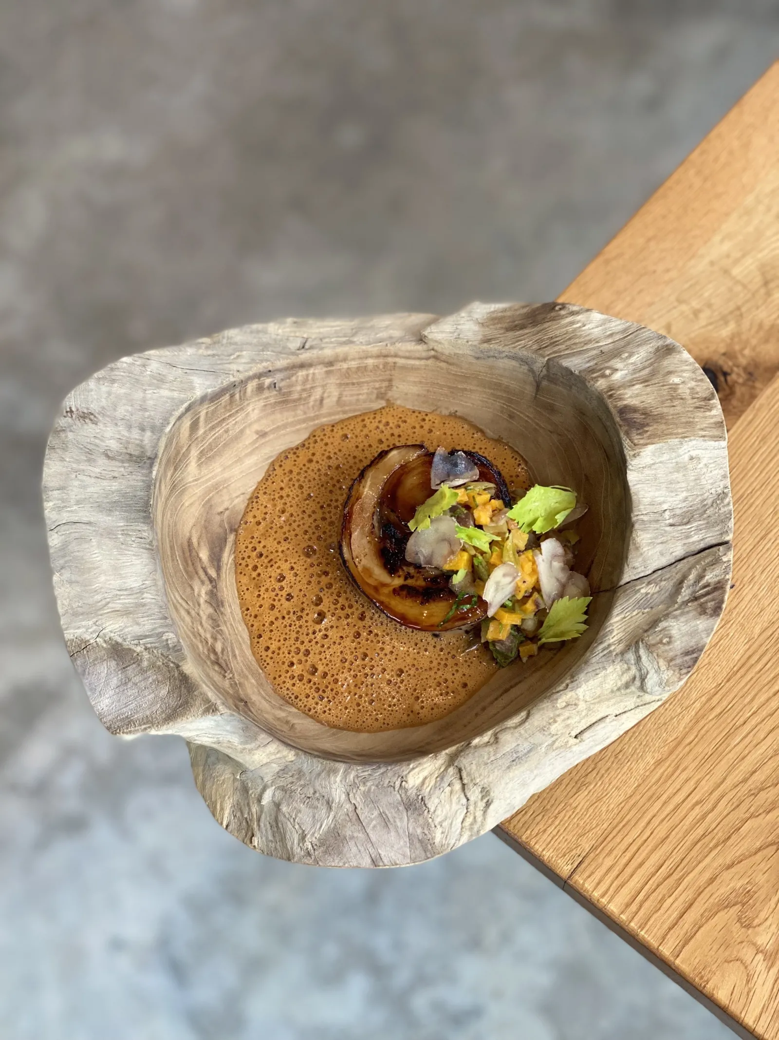 Crepe served in a raw wooden bowl, topped with berries, corn and cream, presented on a wooden table in Bordeaux