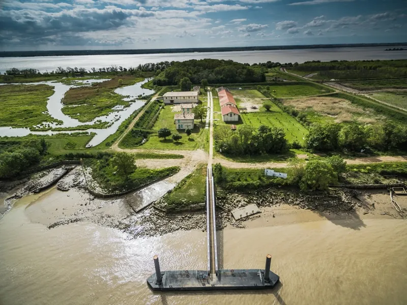 Aerial view of Île Nouvelle in Bordeaux showing a property with buildings, cultivated lands and a river landing stage, surrounded by waterways and marshlands.