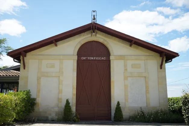 Classical small building with beige façade and brown doors at Château Yon-Figeac in Bordeaux