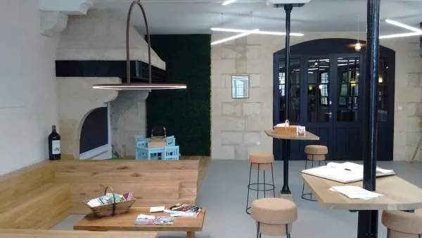 Modern tasting room at Château Lanessan in Bordeaux featuring wooden counter, high stools, black doors and minimalist contemporary décor