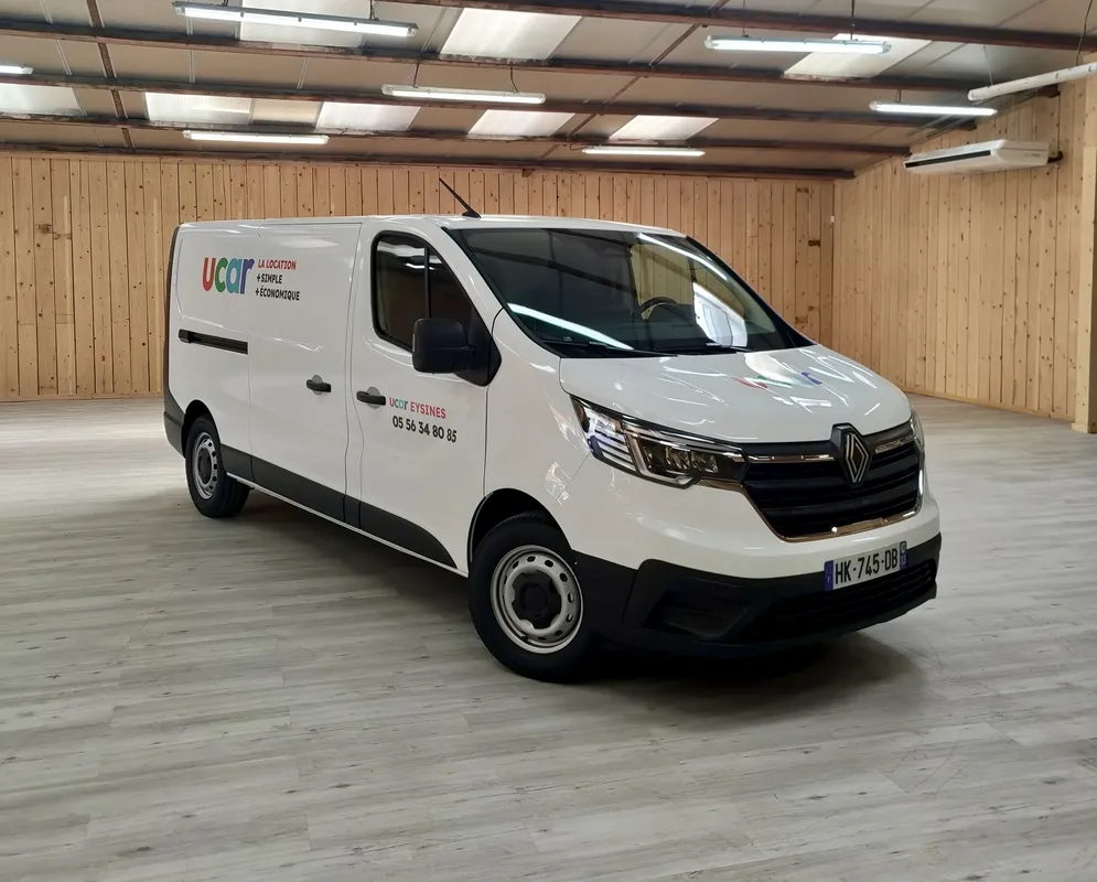 White Renault utility van belonging to UCAR company parked in a covered garage in Bordeaux, with company logo and phone number visible on the side.