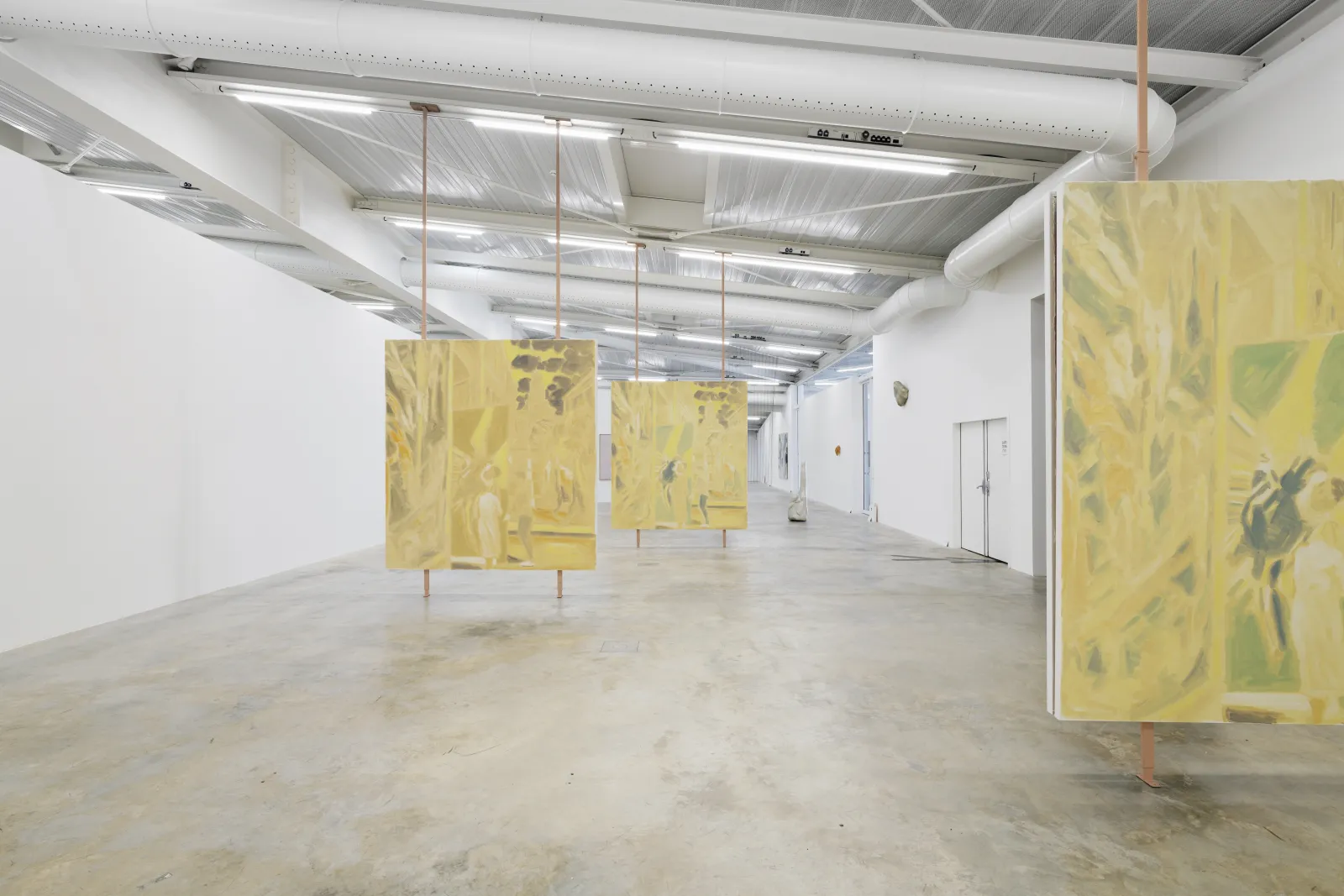 Contemporary art exhibition space at FRAC Nouvelle-Aquitaine in Bordeaux featuring multiple yellow suspended panels with abstract artworks, industrial ceiling with metal beams and fluorescent lighting, raw concrete floor.