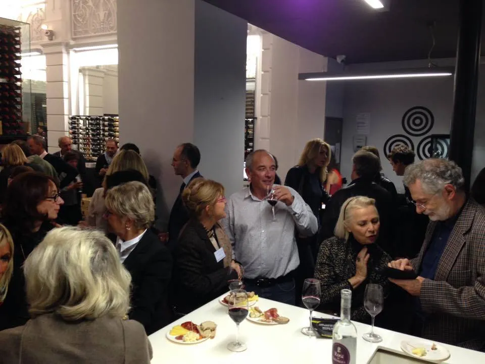 Guests in business attire networking at a wine tasting event at Max Bordeaux Wine Gallery & Cellar, with charcuterie plates and wine glasses on tables.