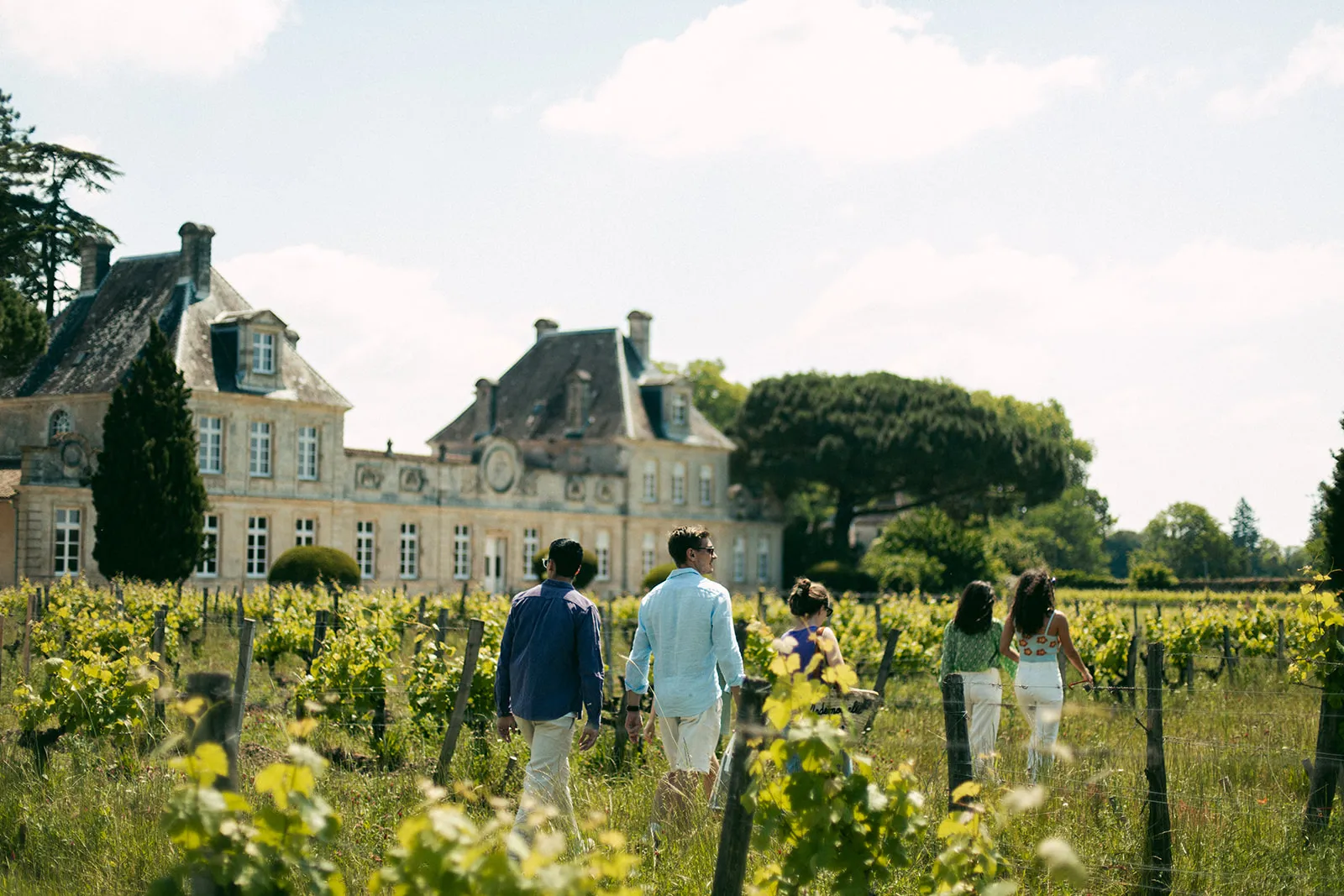 Family walking through the vineyards of Château de Cérons in Bordeaux, with the historic château in the background