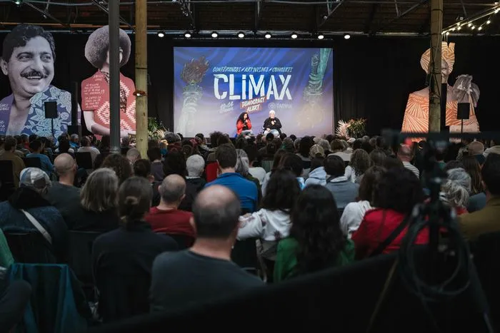 Large crowd watching a stage with a giant screen displaying 'CLIMAX' at the Climax Festival #11 Darwin Experience in Bordeaux, with photo panels and stage lighting in the background.