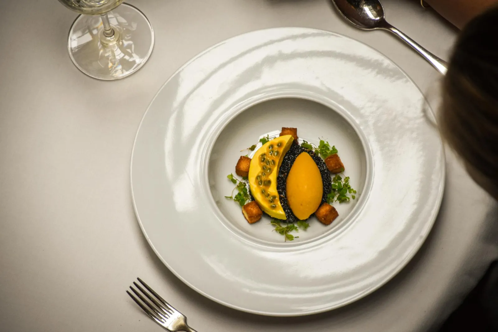 A fine dining plate from Le Chapon Fin restaurant in Bordeaux, featuring a soft-boiled egg with a black shell surrounded by yellow squash slices, golden croutons, and fresh parsley on a white plate.