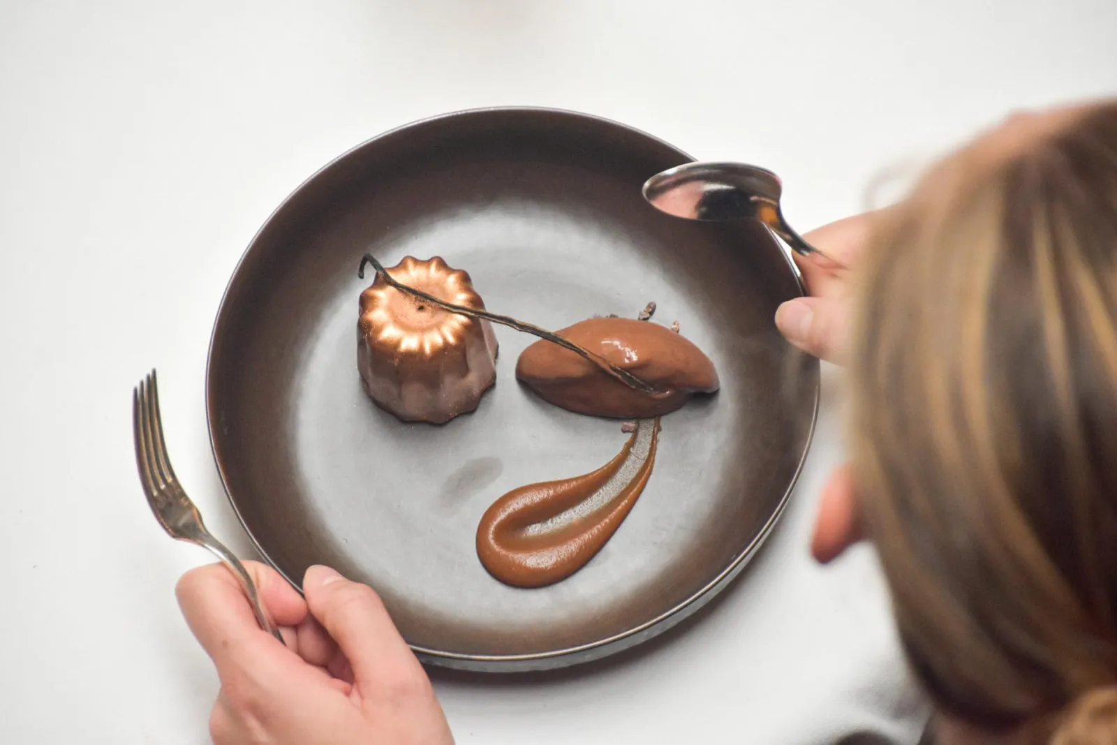 Chef presenting a plate with an artistic chocolate composition featuring a smiling face, at Le Chapon Fin restaurant in Bordeaux