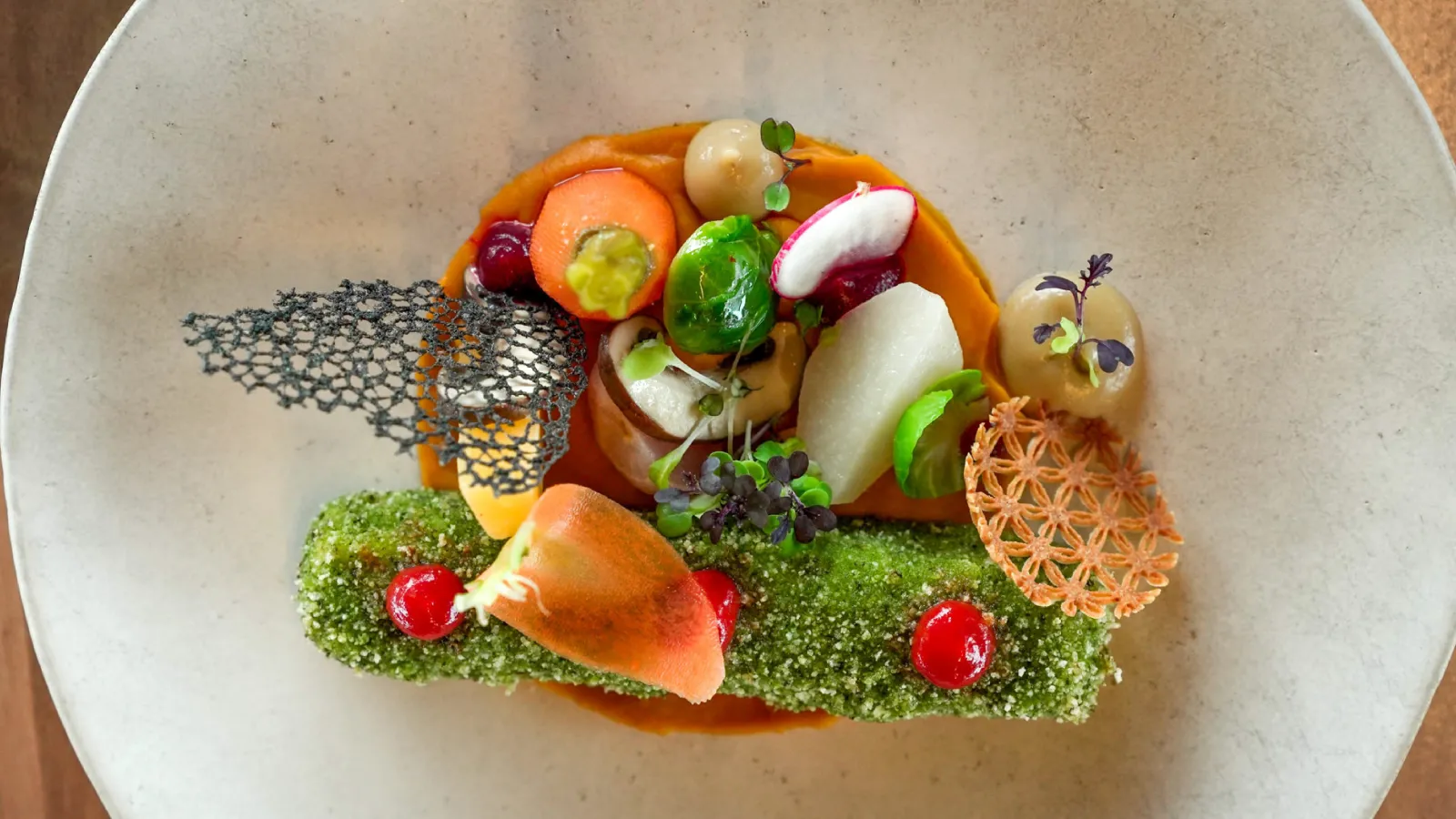 Fine dining plate with vibrant vegetables, green mousse, black lace tuile, fruit pearls and edible flowers, presented at La Terrasse Rouge in Bordeaux