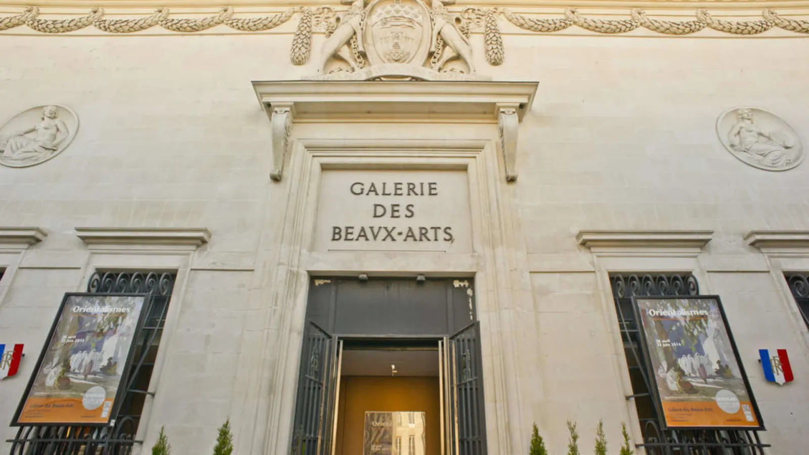 Entrance facade of the Galerie des Beaux-Arts in Bordeaux, featuring classical architectural details, sculptures, and French flags.