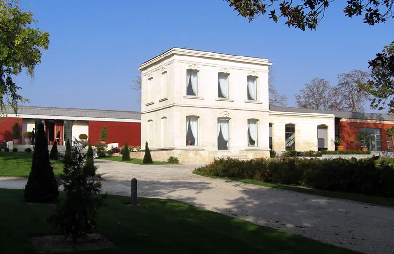 Luchey-Halde Estate in Bordeaux: white two-story building with regular windows, adjacent red structure, paved driveway and landscaped gardens