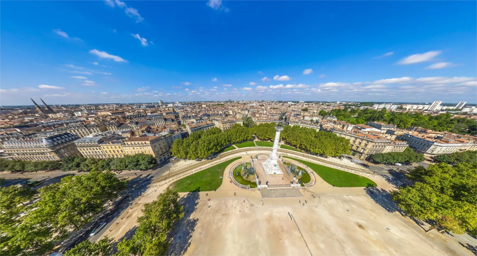 Aerial view of the Esplanade des Quinconces in Bordeaux featuring the Girondins Monument in the center, surrounded by gardens and trees, overlooking Haussmann-style buildings