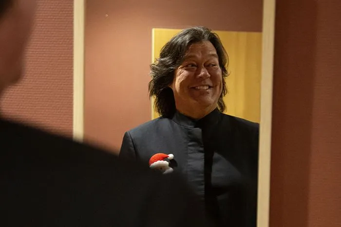 A smiling woman in a black jacket wearing a red and white Santa badge at the Radio Classique Christmas Concert in Bordeaux
