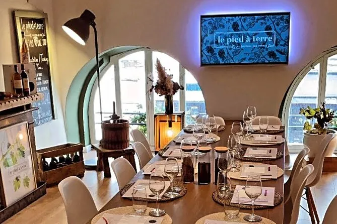 Elegant dining room with set table, wine glasses, large panoramic windows overlooking Bordeaux, restaurant logo displayed on screen, design floor lamp and refined decor.