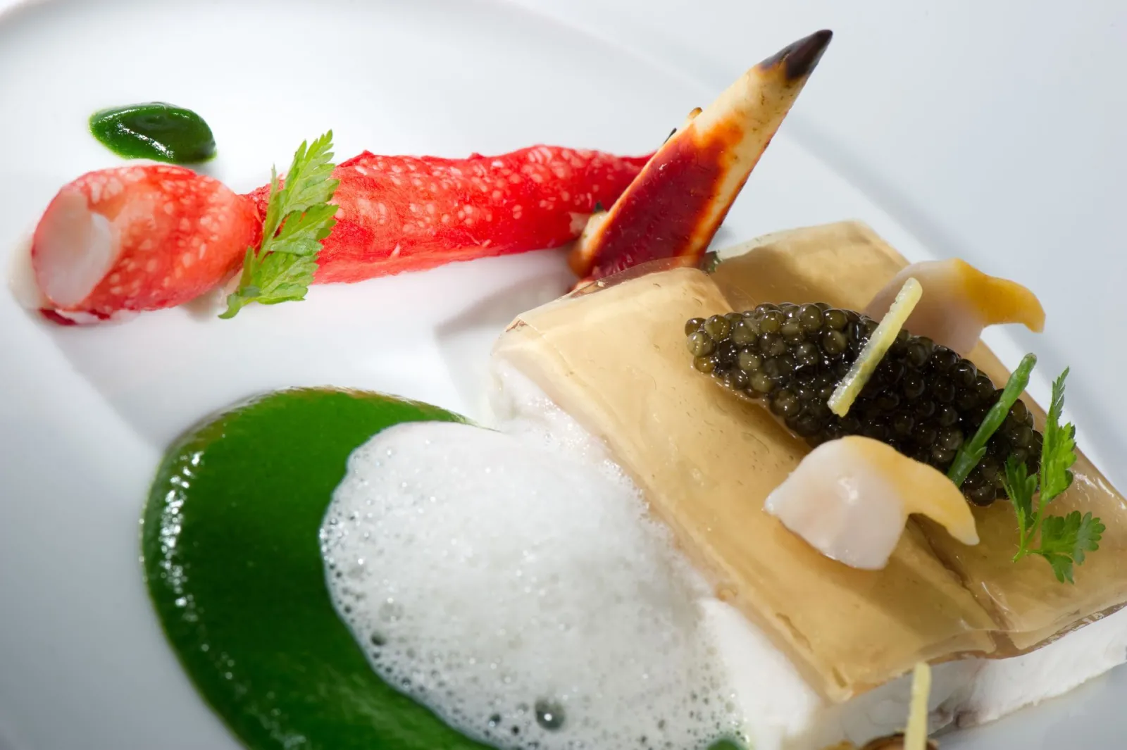Fine dining plate from Le Pressoir d'Argent Gordon Ramsay in Bordeaux featuring foie gras with caviar, green foam, strawberry preparation and quenelle, garnished with fresh herbs
