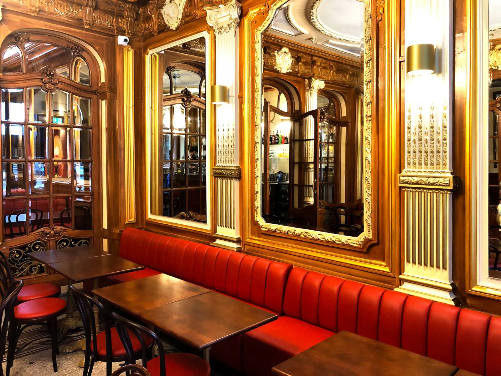 Elegant interior of QuatrèS Café in Bordeaux featuring red upholstered seating, wooden tables, ornate gilt mirrors and belle époque style glass doors