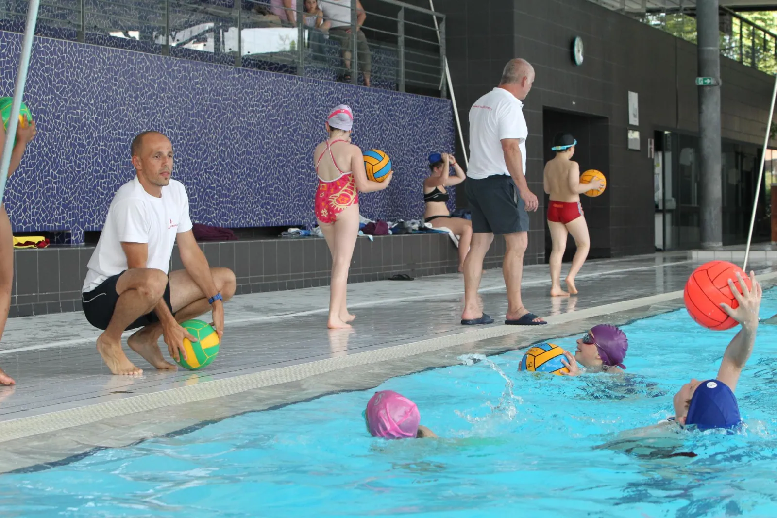 Water polo training session at Bordeaux's Tissot municipal swimming pool with children in the water and a coach on the pool deck