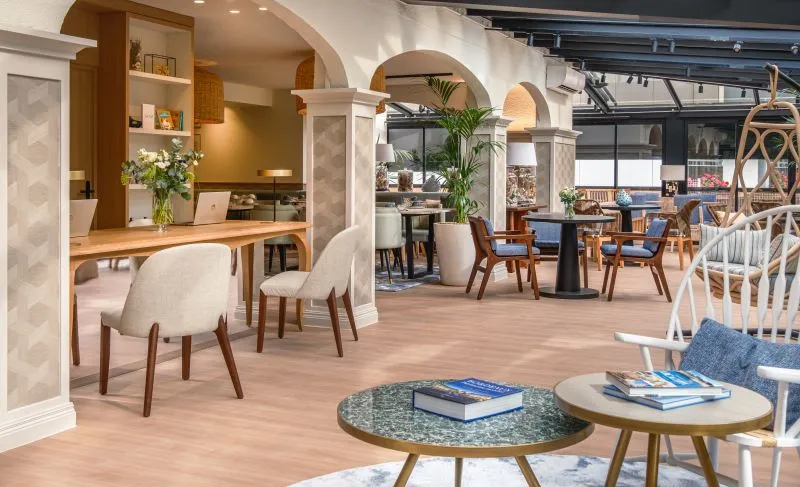 Elegant lobby of Arcanse by Inwood hotel in Bordeaux featuring reception areas, modern seating with wooden and blue furnishings, large windows, and contemporary décor