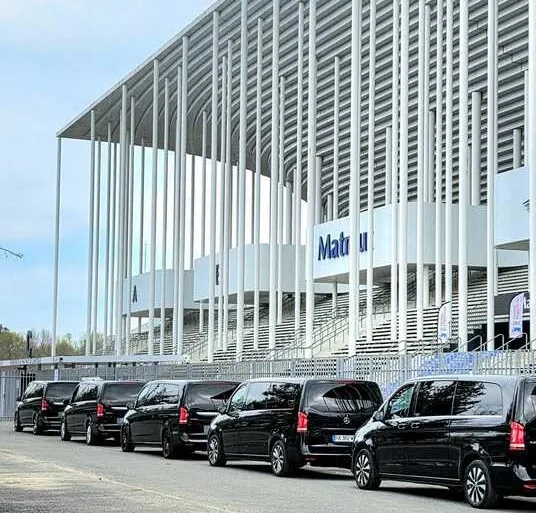 Row of black luxury vehicles parked in front of Matmut Stadium in Bordeaux, professional transportation service