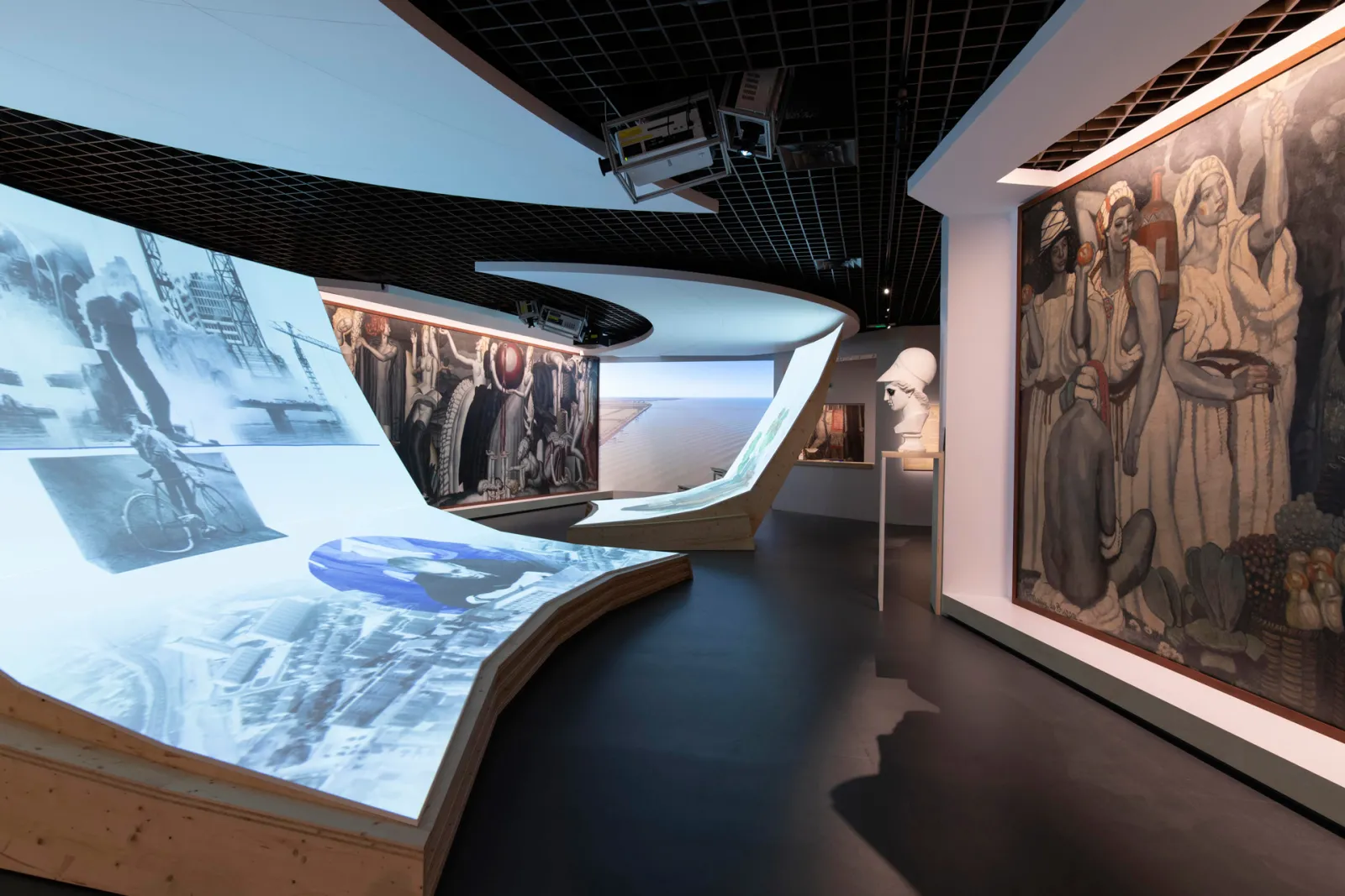 Interior view of the Aquitaine Museum in Bordeaux featuring illuminated interactive displays, historical mural paintings, sculpture, and digital exhibition elements.