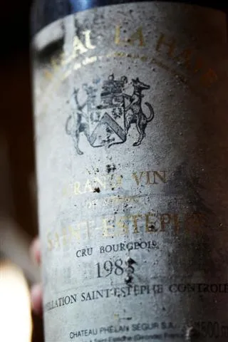 Vintage 1985 red wine bottle from Château La Haye, Bordeaux, labeled as cru bourgeois with aged and dusty label.