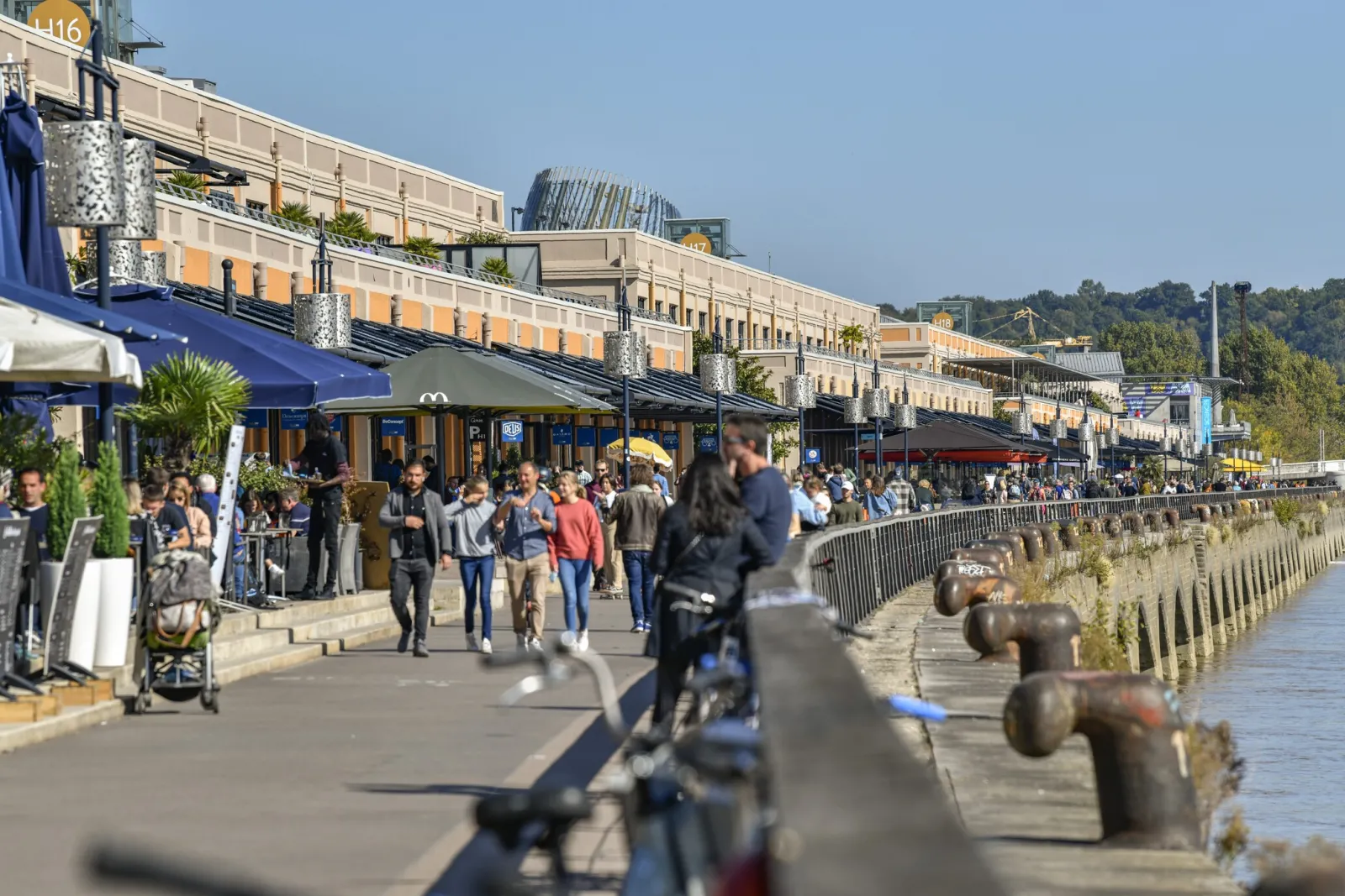 Waterfront promenade at Bord'eau Village in Bordeaux with restaurants, shops and visitors enjoying the riverside setting