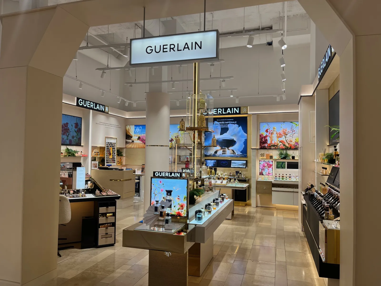 Guerlain luxury boutique at Galeries Lafayette in Bordeaux, showcasing cosmetics and beauty products with illuminated displays and digital screens.