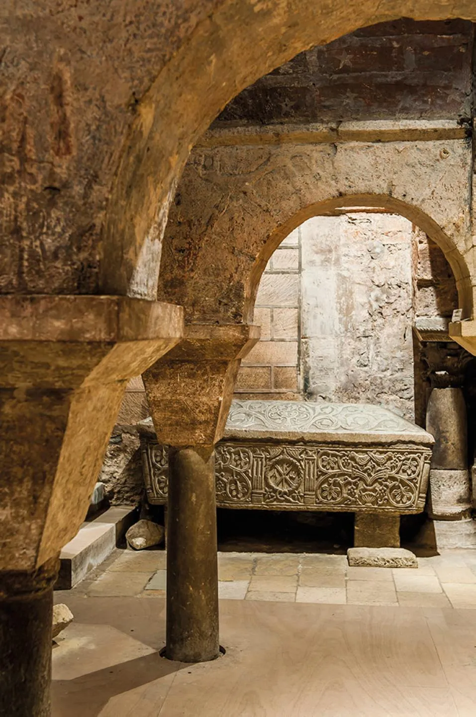 Interior of the Saint-Seurin archaeological site in Bordeaux featuring Roman stone arches, columns, and a sarcophagus with geometric decorative patterns.