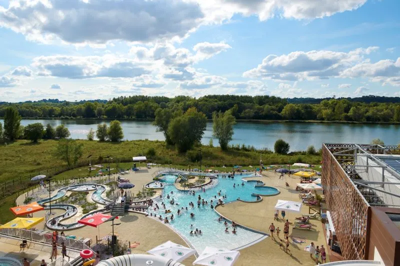 Aerial view of La Calinésie aquatic center in Libourne near Bordeaux, featuring swimming pools, water slides, and recreational areas overlooking lakes and forests.