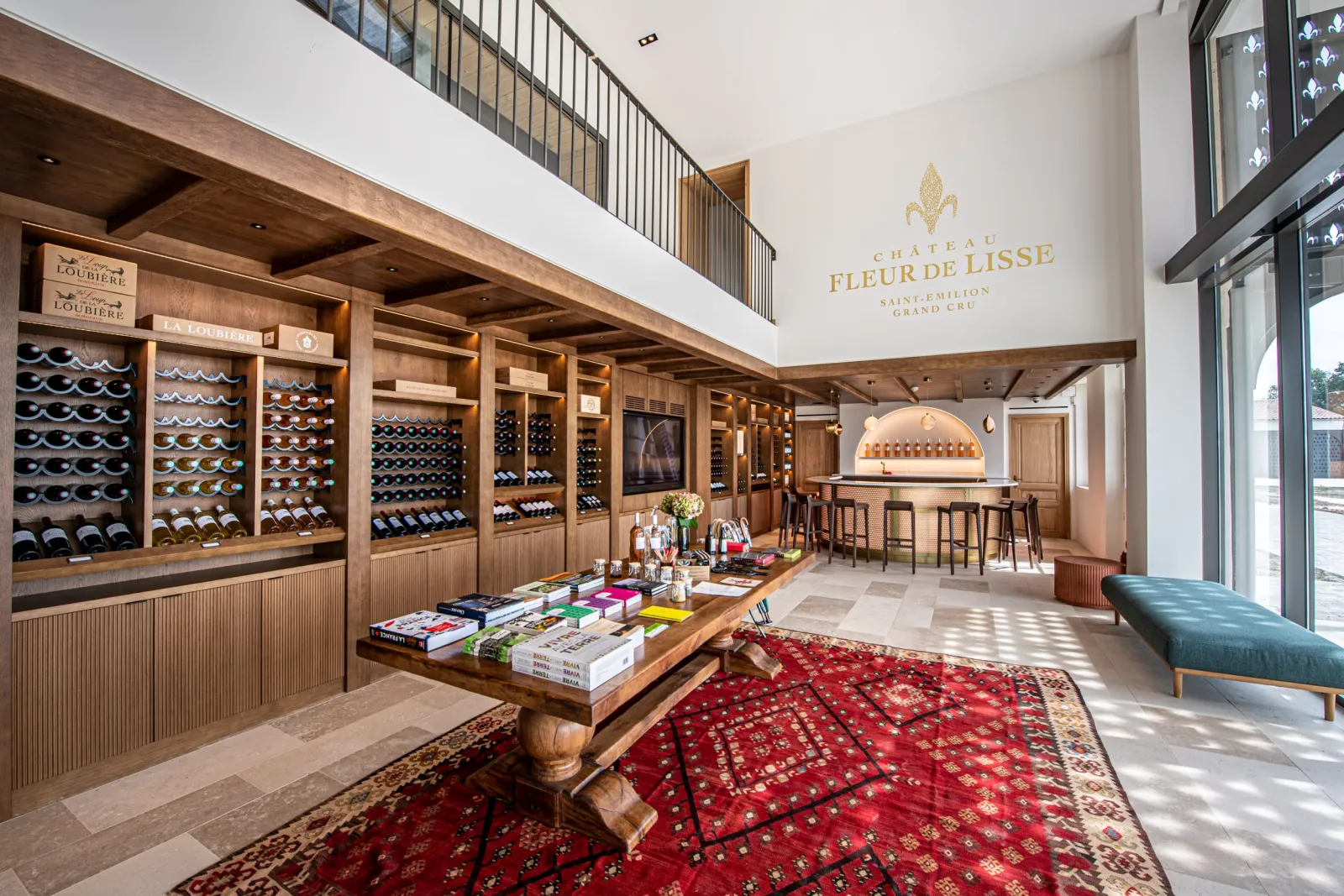 Elegant interior of Château Fleur de Lisse in Bordeaux, featuring wooden wine storage racks filled with bottles, a tasting counter, and refined interior design with white walls and exposed beams.