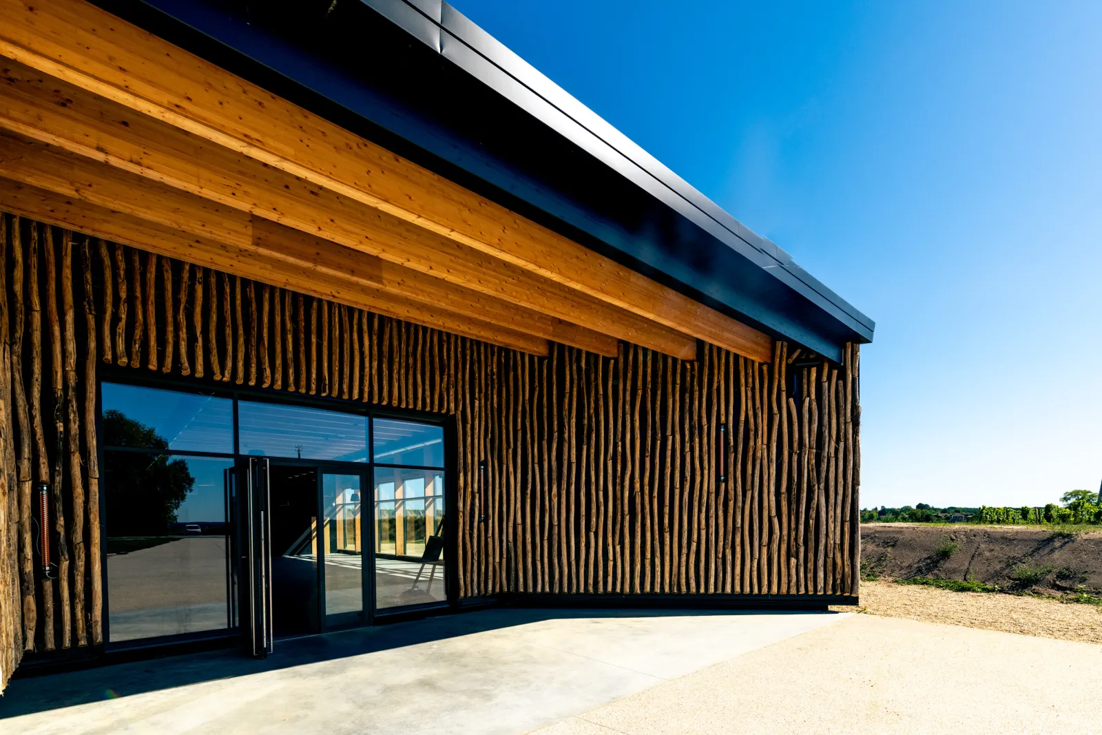 Modern building with corrugated wooden façade and glass windows in a rural landscape near Bordeaux at Château d'Arche