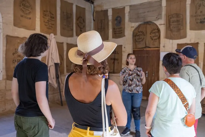 Group of visitors on a guided tour inside the Moulin de Porchères in Bordeaux, with historical grain sacks displayed on the walls