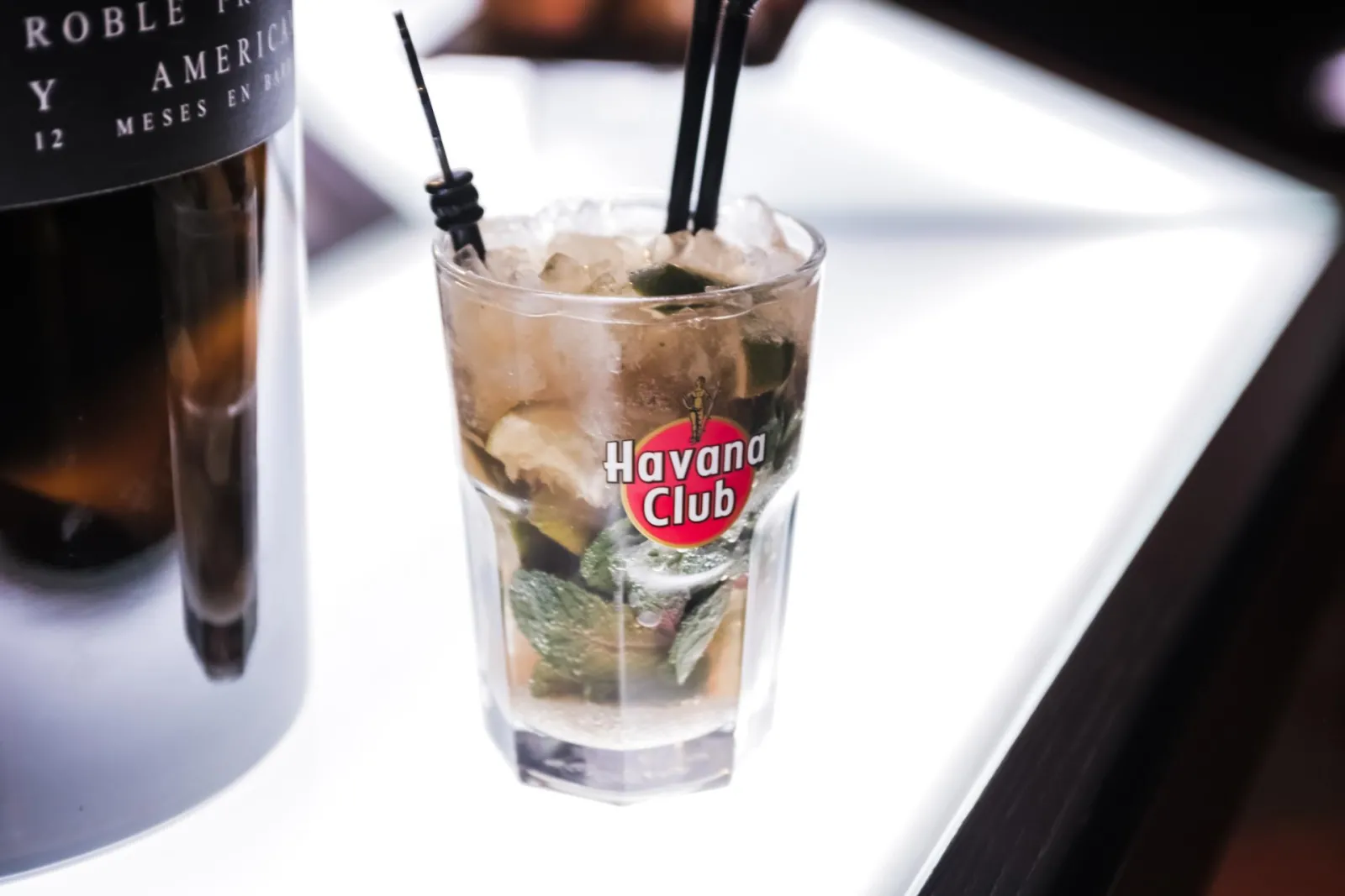 A glass of Havana Club rum filled with ice and fresh mint, paired with a bottle of aged American rum, served in Bordeaux.
