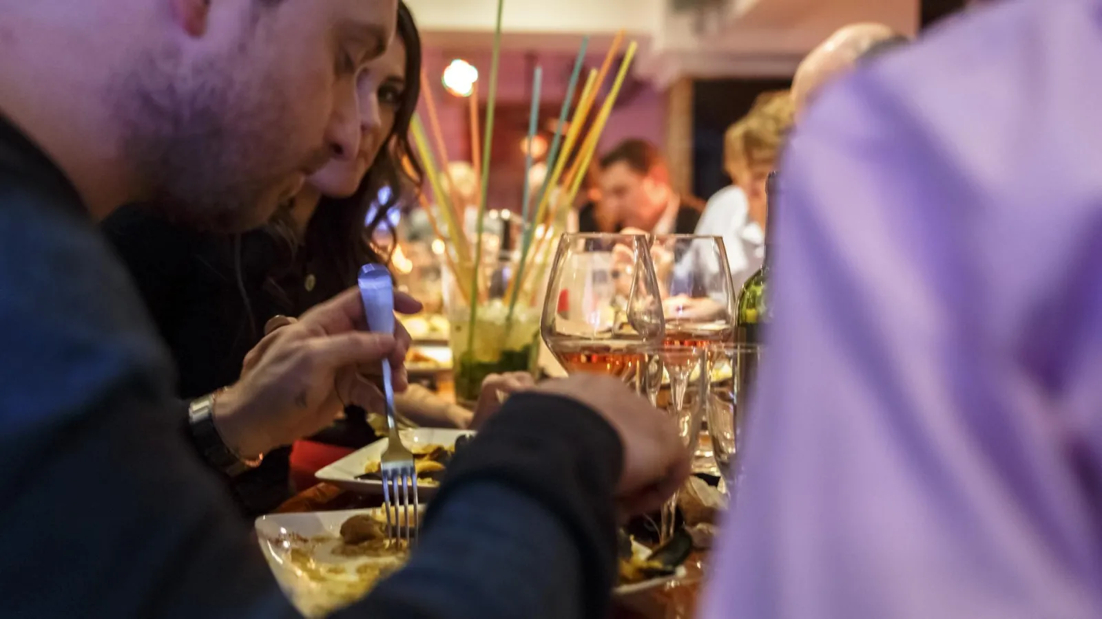 Diners enjoying a meal at a decorated table with wine glasses, flowers and candles at Bodega Bodega restaurant in Bordeaux