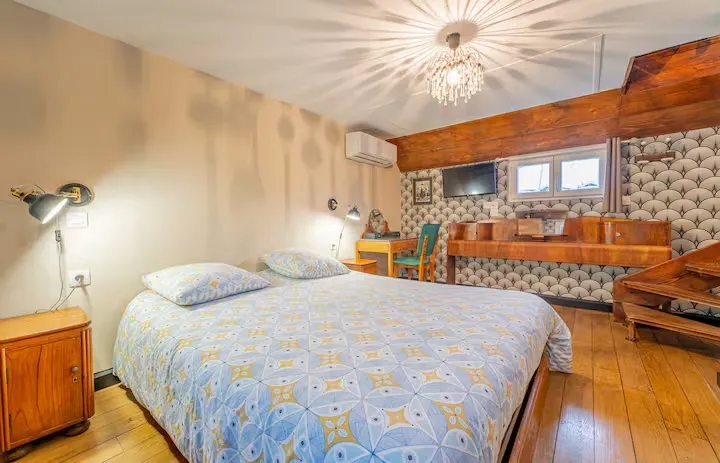 Spacious bedroom on a houseboat with double bed, wooden furniture, exposed beam, and kitchenette in the corner