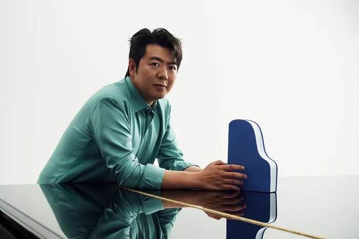 Young man in green shirt presenting a blue building model at the Lang Lang Concerto event in Bordeaux