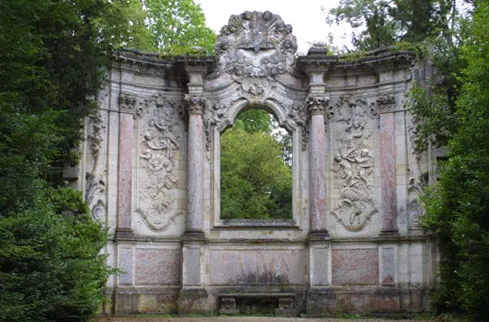 Ornamental ruin of the Taillan château near Bordeaux, stone facade with sculpted columns and central arch, surrounded by lush greenery