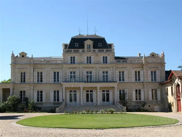 Main façade of Château Giscours in Bordeaux, a grand neoclassical mansion with mansard roofs, balustrades and ornamental stonework, overlooking a circular lawn