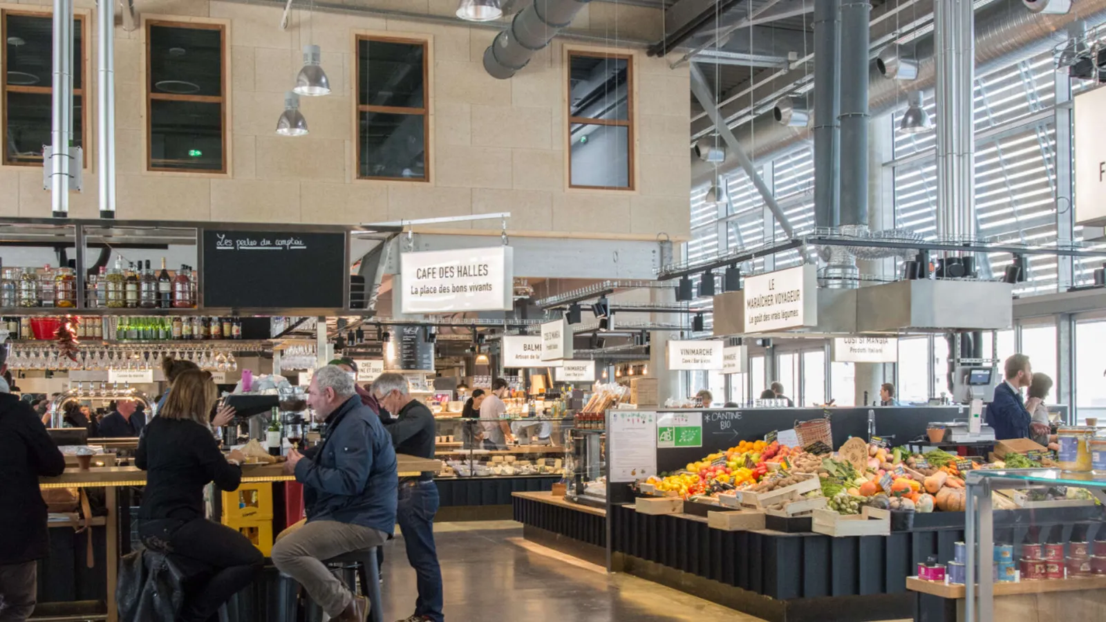 Interior view of Halles de Bacalan in Bordeaux, covered market with produce stalls, food counters and customers browsing the space.