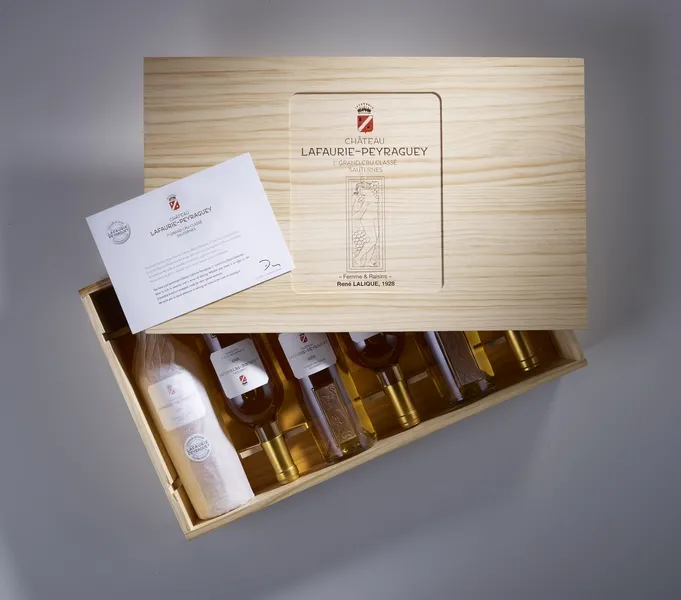 Tasting box of Château Lafaurie-Peyraguey featuring multiple bottles of white Sauternes wine, presented in a wooden case with branding and accompanying letter.