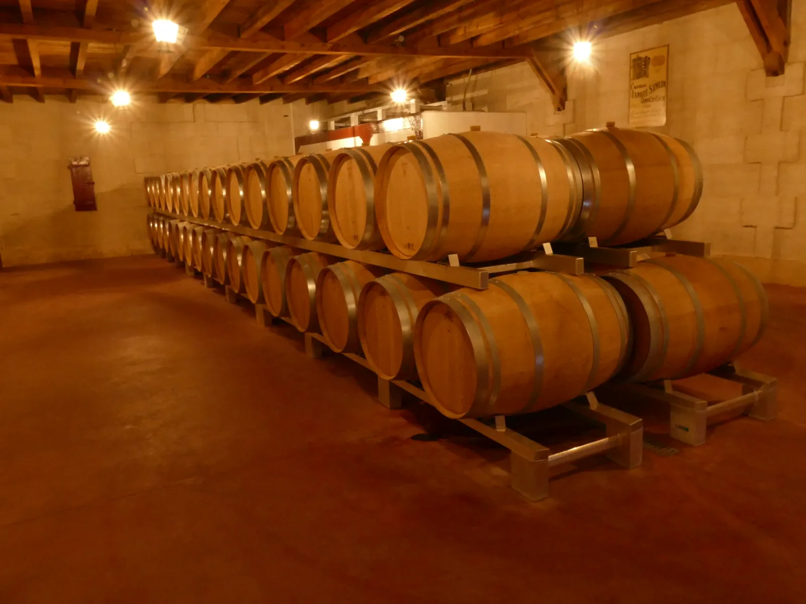 Aging cellar with wooden barrels stacked in two rows inside an illuminated winery at Château Laniote in Bordeaux