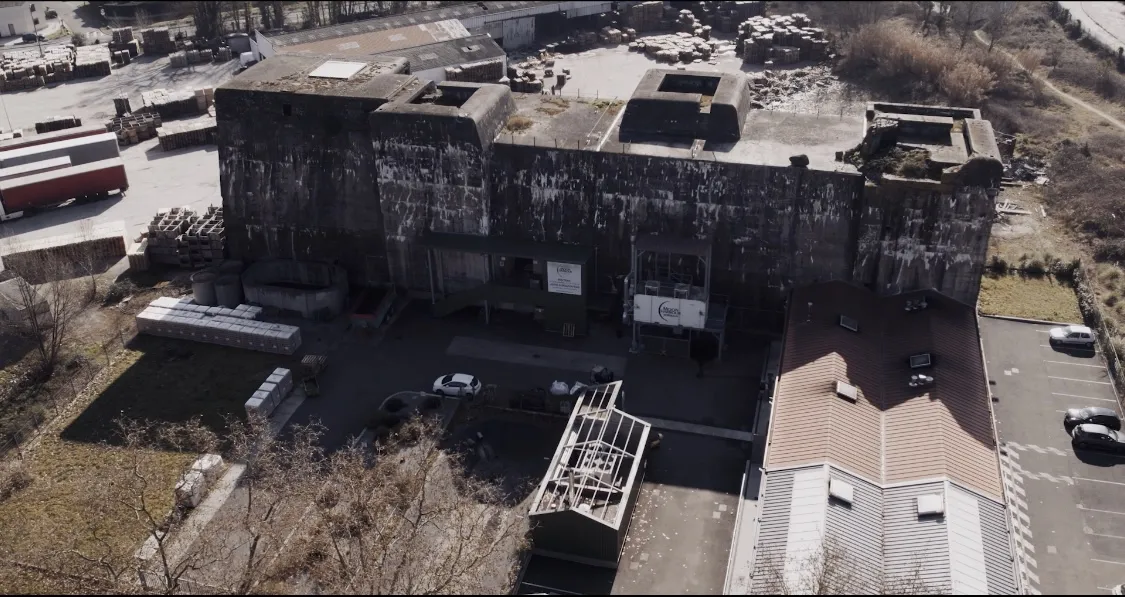 Aerial view of Moon Harbour distillery in Bordeaux, featuring black industrial buildings with clerestory roofs, parking area, storage facilities and metal structures