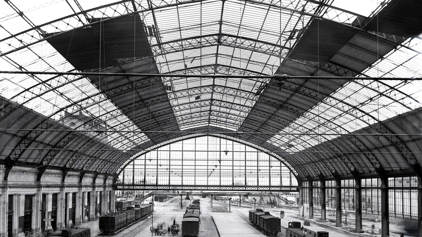 Interior of Bordeaux Saint-Jean railway station featuring its glass and steel roof, displaying platforms and railway tracks under 19th-century Beaux-Arts architecture.